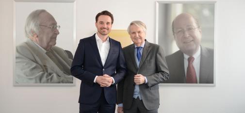 Drei Generationen der Unternehmerfamilie Müller: Dr. Claus-M. Müller mit seinem Sohn Nicolaus vor den Porträts seines Vaters und Firmengründers Heinrich W. Müller (links; †2010) und seines Bruders Dr. Bertram R. Müller (†2012).